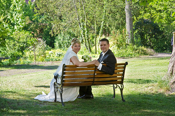 Hochzeitspaar auf einer Bank im Park